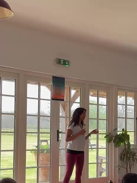 Sangi leading a session in front of tall windows