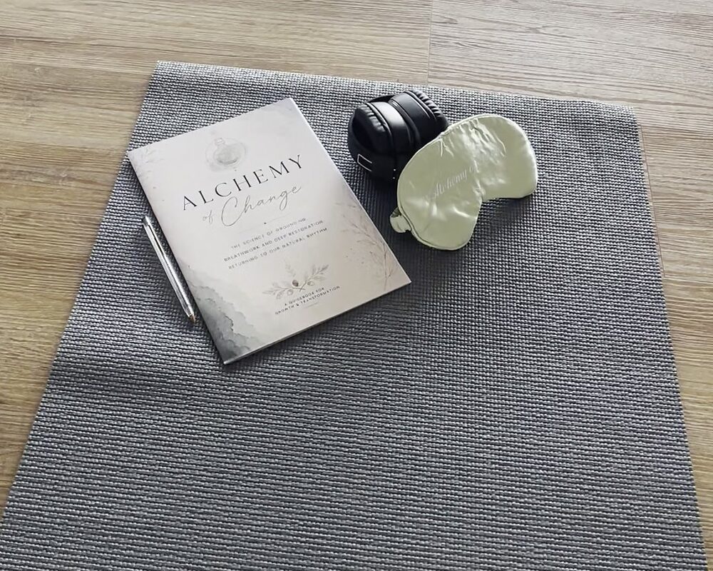 An Alchemy of Change workbook, headphones and eye mask laid on a mat
